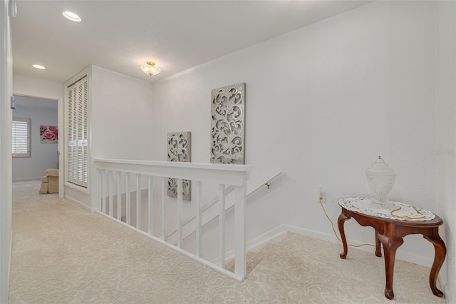 hall featuring recessed lighting, baseboards, light colored carpet, and an upstairs landing