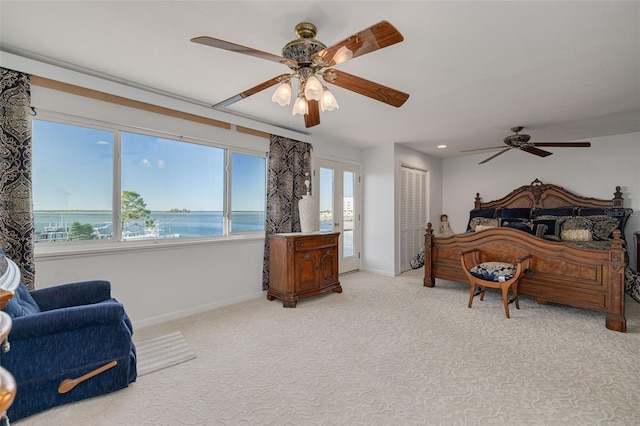 bedroom featuring light carpet, baseboards, a water view, french doors, and a closet