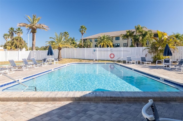 community pool with a patio and fence