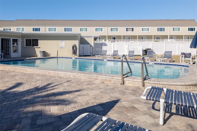 community pool with a patio area and fence