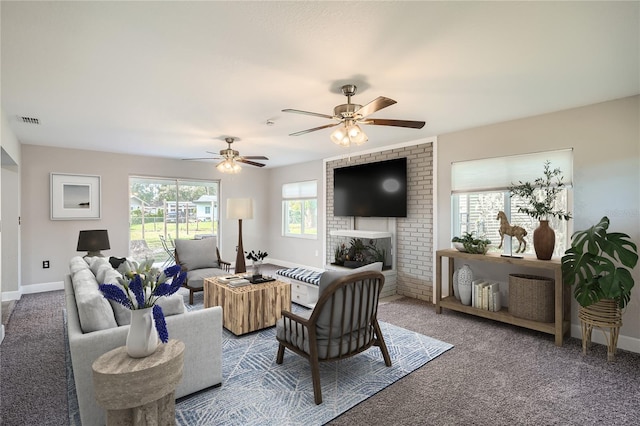 carpeted living room with ceiling fan and a fireplace