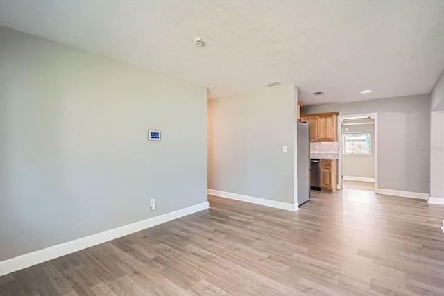 unfurnished living room featuring a textured ceiling and light wood-type flooring