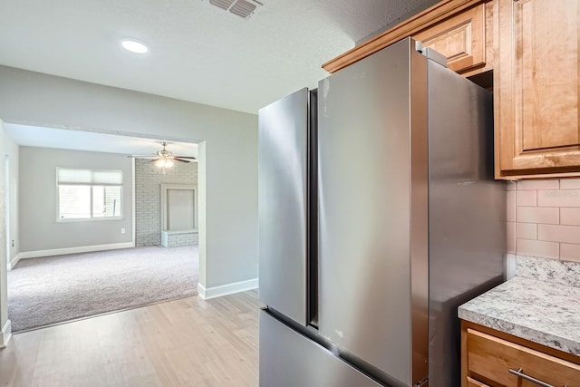 kitchen with stainless steel refrigerator, ceiling fan, backsplash, light hardwood / wood-style floors, and a textured ceiling