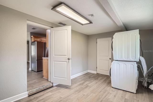 interior space featuring stacked washing maching and dryer, light hardwood / wood-style floors, and a textured ceiling