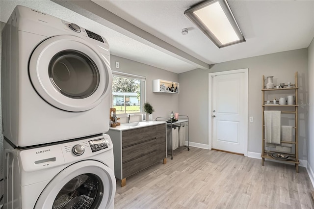 washroom featuring light hardwood / wood-style floors, stacked washer and clothes dryer, and sink