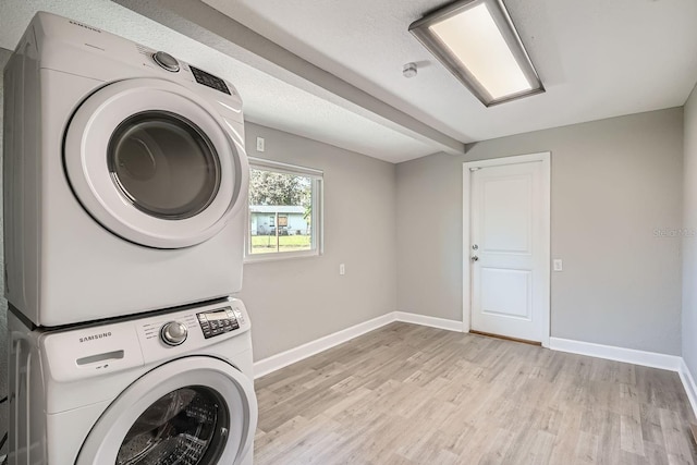 laundry area with light wood-type flooring and stacked washer / dryer