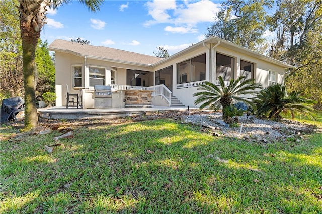 view of front facade with a front yard, a sunroom, and exterior kitchen