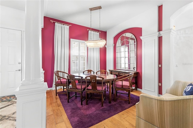 dining room featuring hardwood / wood-style floors, a chandelier, and decorative columns