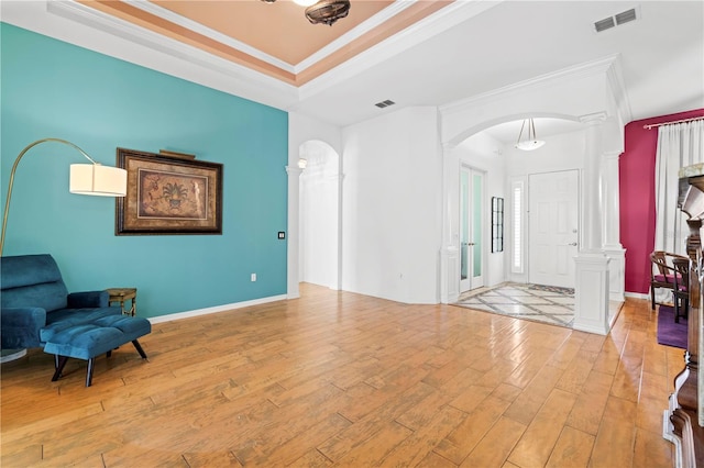 interior space featuring decorative columns, ornamental molding, and light wood-type flooring