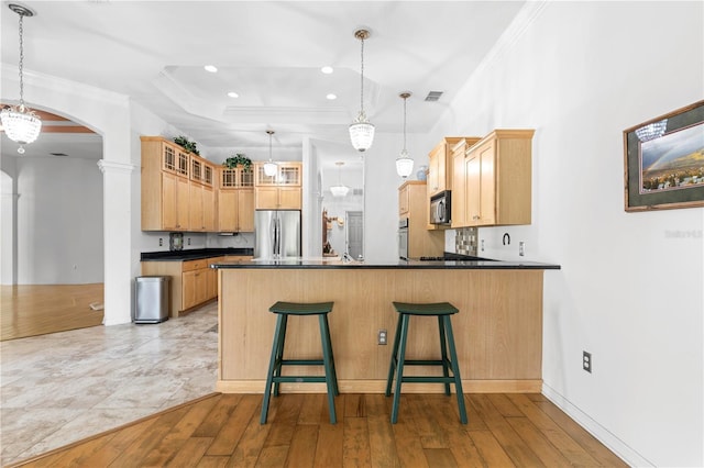 kitchen with pendant lighting, crown molding, light wood-type flooring, and stainless steel appliances