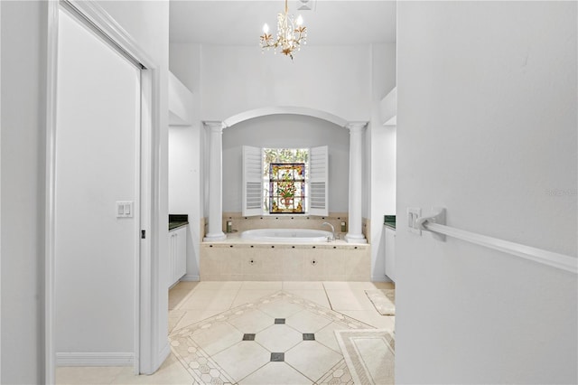 bathroom featuring ornate columns, an inviting chandelier, tile patterned flooring, a relaxing tiled tub, and vanity