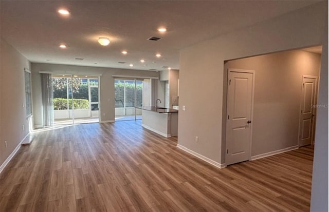 unfurnished living room with wood-type flooring and sink