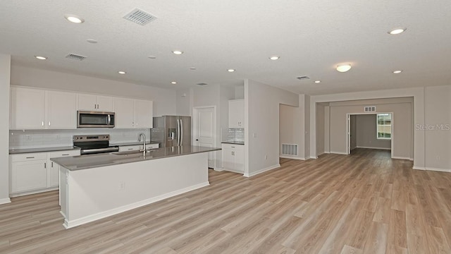 kitchen with sink, white cabinets, stainless steel appliances, a center island with sink, and light wood-type flooring