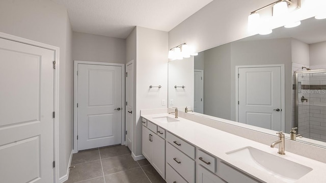 bathroom featuring tile patterned flooring, vanity, a shower with door, and a textured ceiling