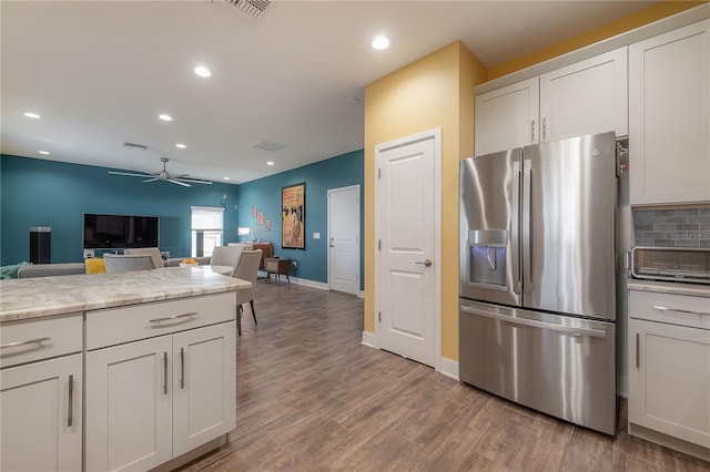 kitchen with decorative backsplash, stainless steel fridge, ceiling fan, hardwood / wood-style flooring, and white cabinets