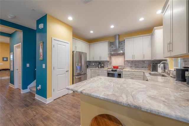 kitchen featuring wall chimney exhaust hood, stainless steel appliances, dark hardwood / wood-style flooring, kitchen peninsula, and white cabinets