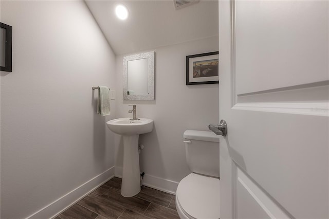 bathroom featuring hardwood / wood-style floors, toilet, lofted ceiling, and sink