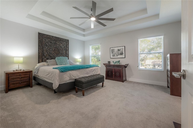 bedroom featuring a raised ceiling, ceiling fan, and light carpet