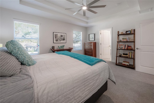 bedroom featuring ceiling fan, carpet floors, and a tray ceiling