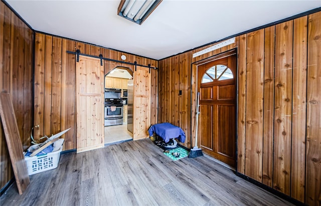 entrance foyer with wood walls, wood-type flooring, and crown molding