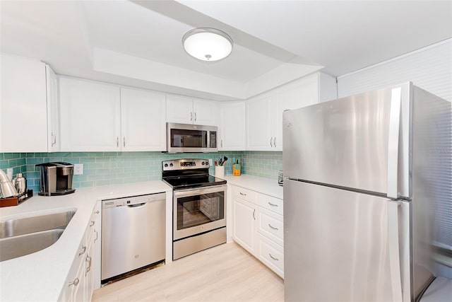 kitchen with sink, decorative backsplash, light hardwood / wood-style floors, white cabinetry, and stainless steel appliances