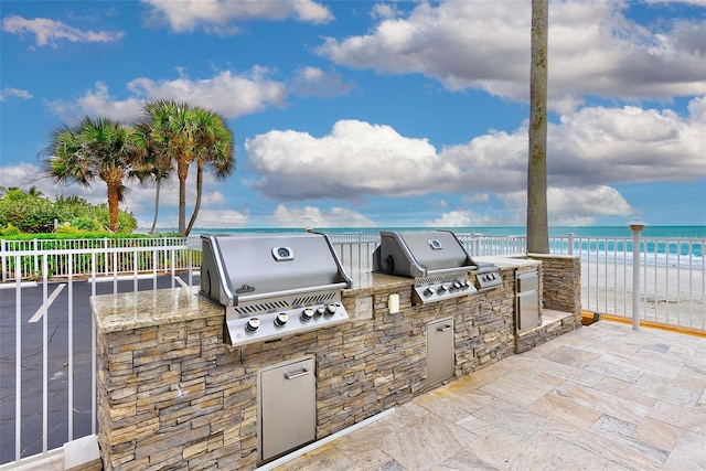 view of patio / terrace featuring a water view, area for grilling, and a view of the beach