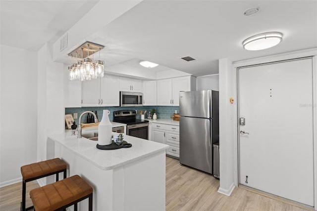 kitchen with white cabinetry, appliances with stainless steel finishes, sink, and decorative light fixtures