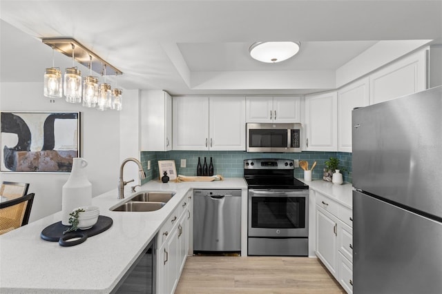 kitchen featuring sink, decorative light fixtures, appliances with stainless steel finishes, white cabinets, and backsplash