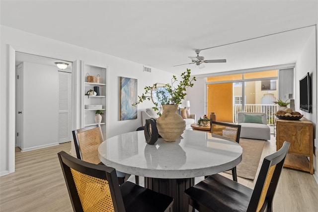 dining area featuring built in shelves, ceiling fan, floor to ceiling windows, and light hardwood / wood-style floors