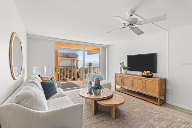 living room featuring expansive windows, ceiling fan, and light hardwood / wood-style flooring