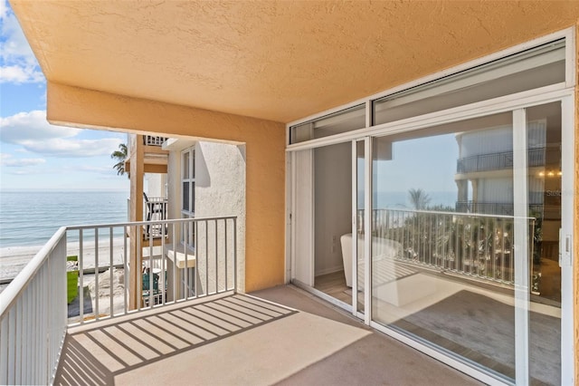 balcony with a water view and a view of the beach