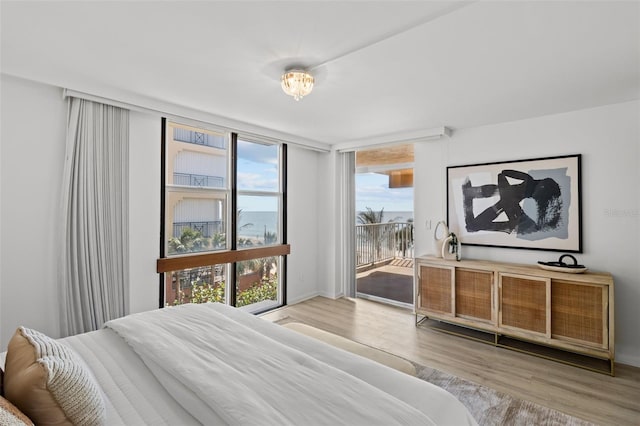 bedroom with wood-type flooring, floor to ceiling windows, and access to outside