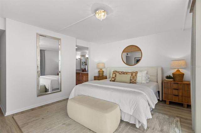 bedroom featuring ensuite bathroom and light hardwood / wood-style floors