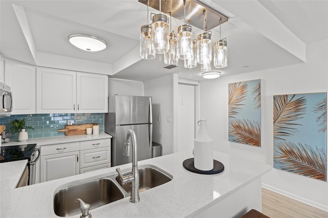 kitchen featuring sink, light stone counters, appliances with stainless steel finishes, white cabinets, and backsplash