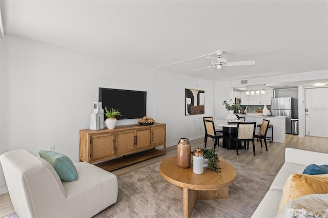 living room with sink, ceiling fan, and light wood-type flooring