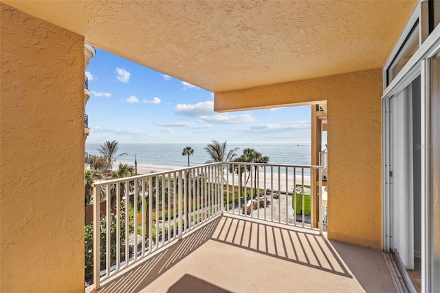 balcony featuring a water view and a beach view