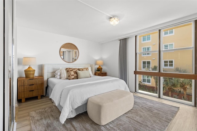 bedroom featuring multiple windows, wood-type flooring, and floor to ceiling windows