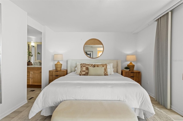 bedroom with connected bathroom and light hardwood / wood-style flooring