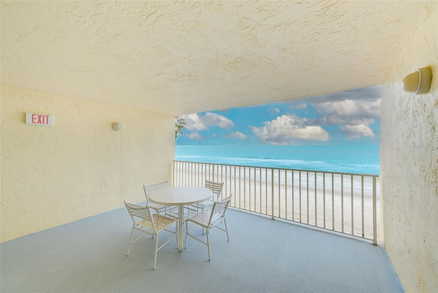 balcony with a water view and a view of the beach