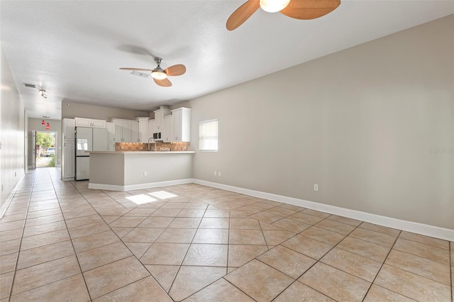 kitchen with kitchen peninsula, light tile patterned floors, white cabinetry, and a wealth of natural light