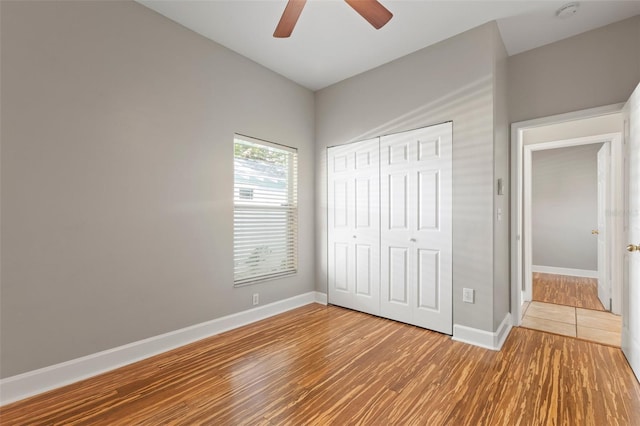 unfurnished bedroom featuring ceiling fan, a closet, and hardwood / wood-style flooring