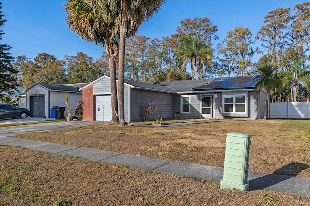 ranch-style home featuring solar panels, a garage, and a front lawn