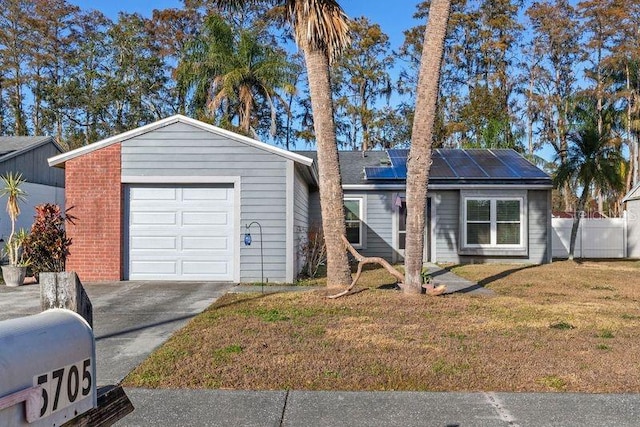 ranch-style home with a front lawn, a garage, and solar panels