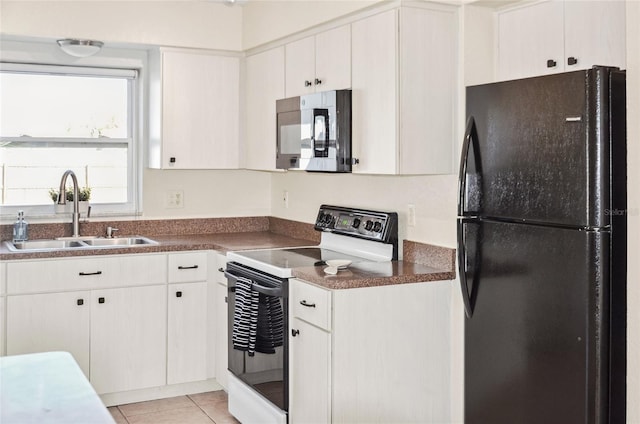 kitchen with range with electric cooktop, light tile patterned flooring, white cabinetry, sink, and black fridge