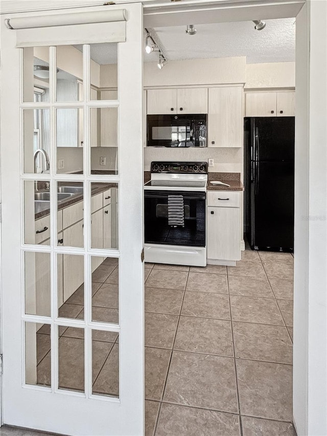 kitchen with rail lighting, sink, light tile patterned floors, and black appliances