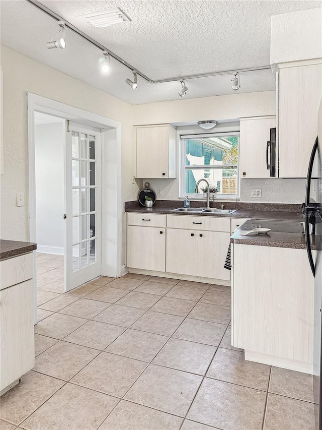 kitchen with sink, light tile patterned floors, a textured ceiling, and french doors