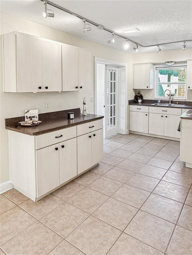 kitchen featuring sink, light tile patterned floors, white cabinets, and a textured ceiling