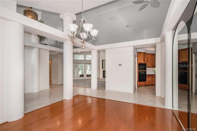 interior space with ceiling fan with notable chandelier and light hardwood / wood-style floors