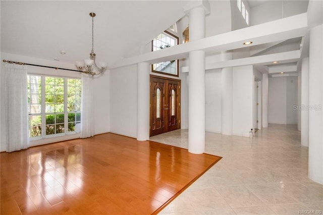 foyer entrance with high vaulted ceiling, a notable chandelier, and light wood-type flooring