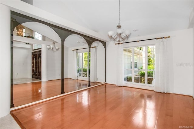 spare room with wood-type flooring and a notable chandelier